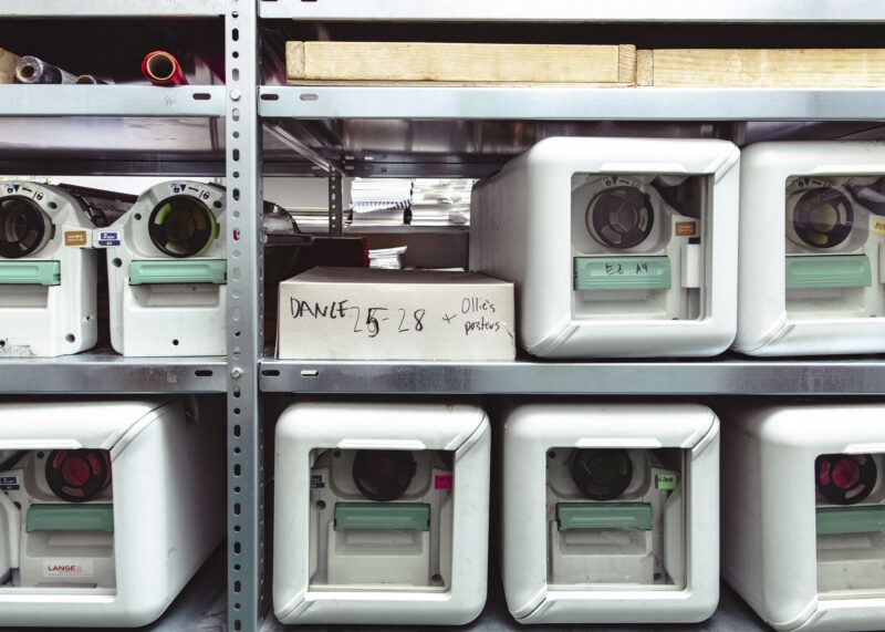 Close up of metal shelves holding risograph color drums in cases.