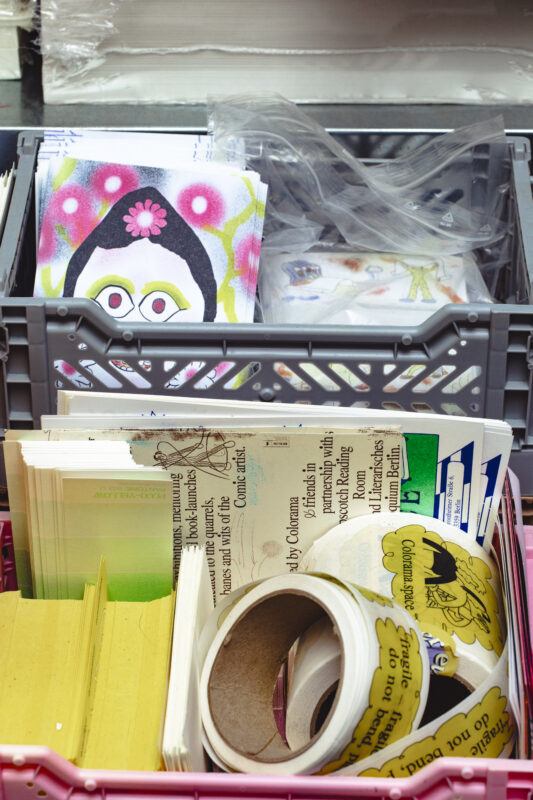 Close up of containers of printed items in Colorama's project space.