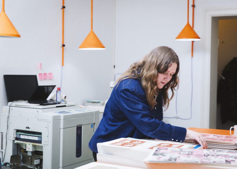Johanna Maierski leaning over a table of pages for a book project.