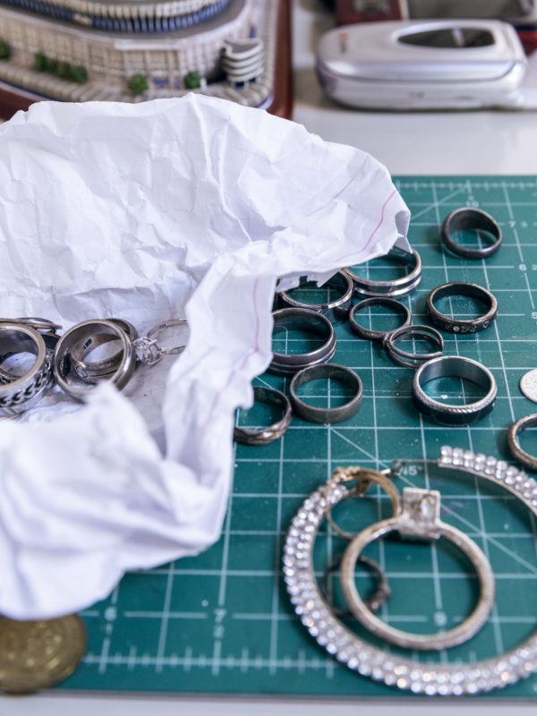 Rings sit on a green gridded surface with white lines, next to a pile of additional rings sitting in a wrinkled piece of paper that presumably was once holding all of the rings.
