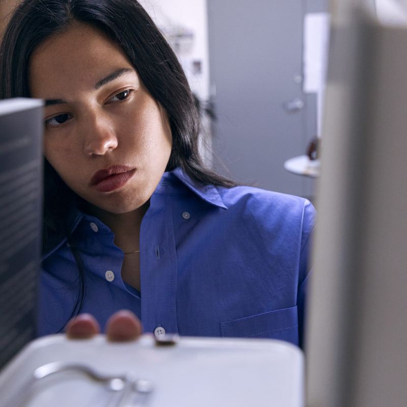 Artist Rose Salane looks pensively through her bookshelves.