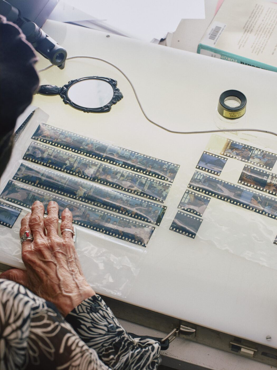 Alanis Obomsawin examines photographic film negatives on a light table.