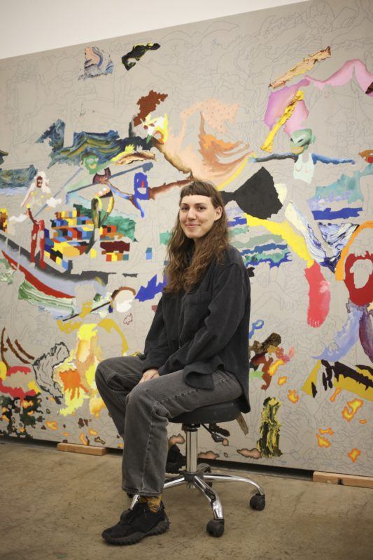 Artist Cindy Phenix sitting in her studio before a large scale unfinished canvas.