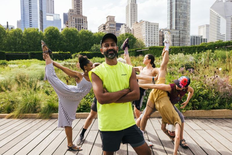 Brendan Fernandes standing in front of dancers in Lurie Garden at Millennium Park, Chicago, Illinois.