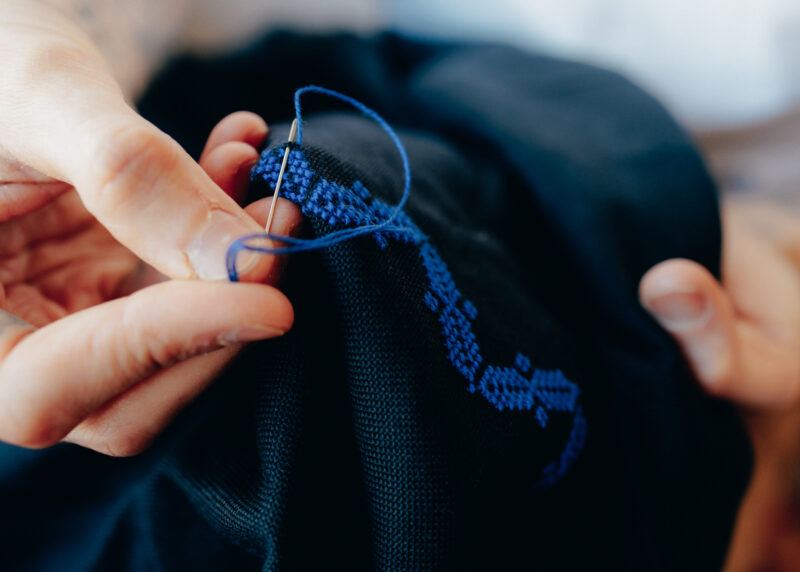 Close up of hands holding a needle and thread.