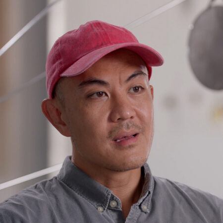Tuan Andrew Nguyen wearing a red cap and gray button-up shirt.