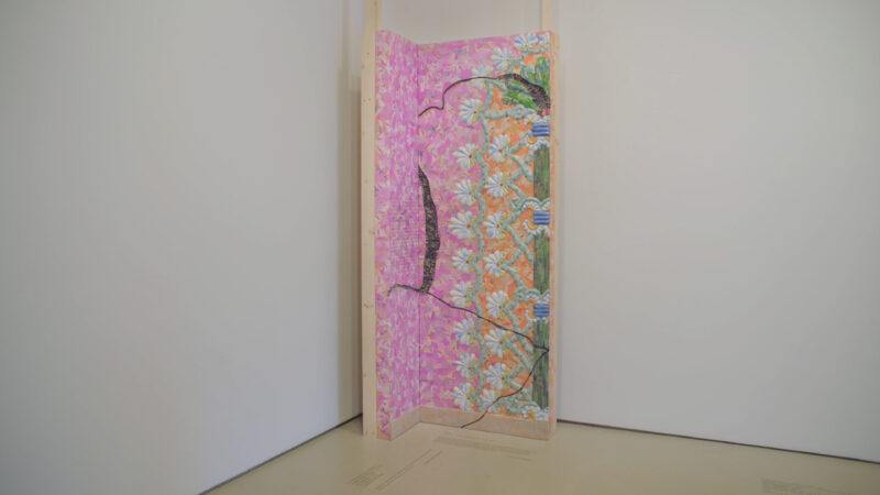 A paper mosaic panel with floral patterns and abstract designs displayed in a corner against a white wall.